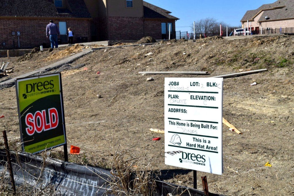 Our official sold sign and Bryan and Cade walking the property in the background