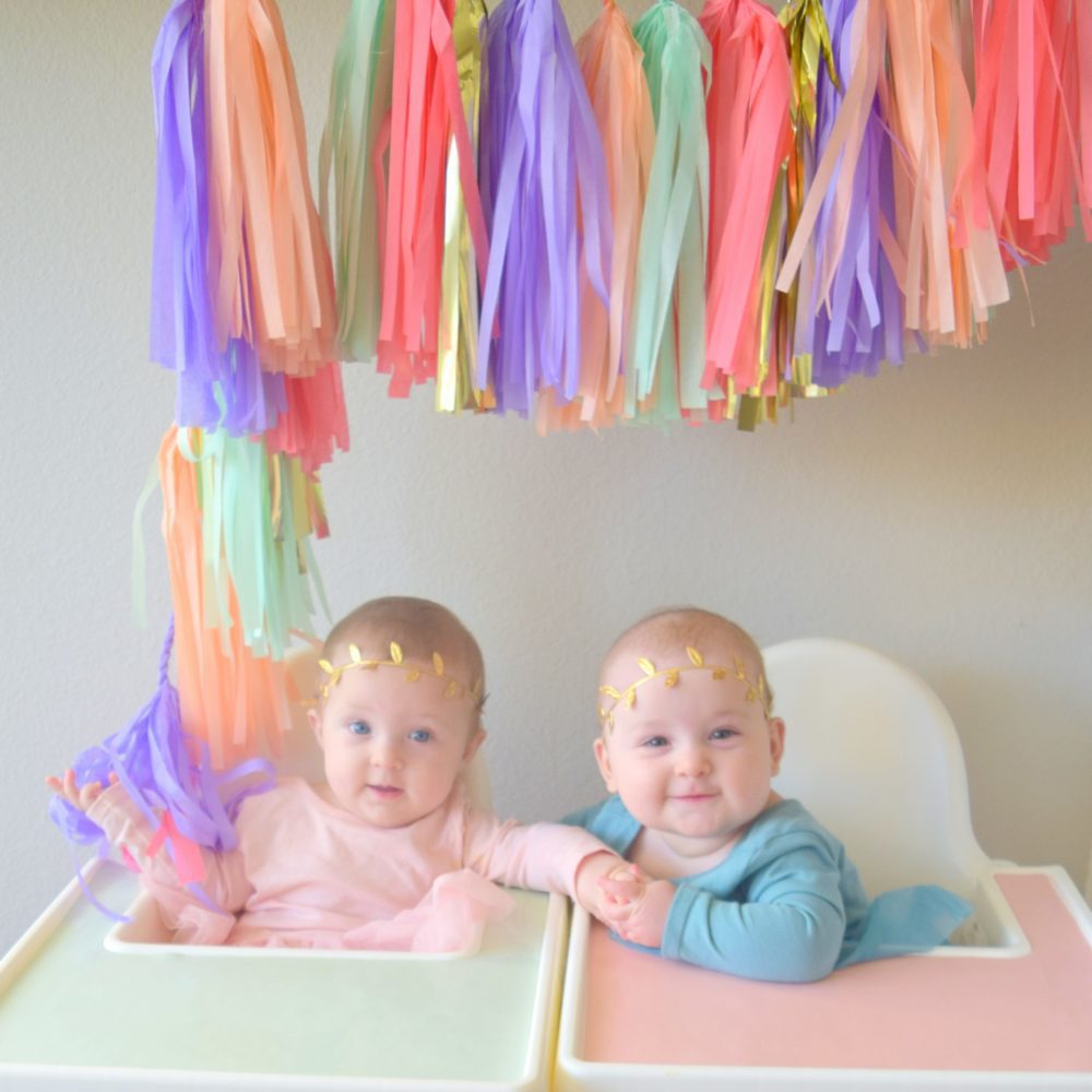 twin girls 6 month baby pictures colorful tassel garland