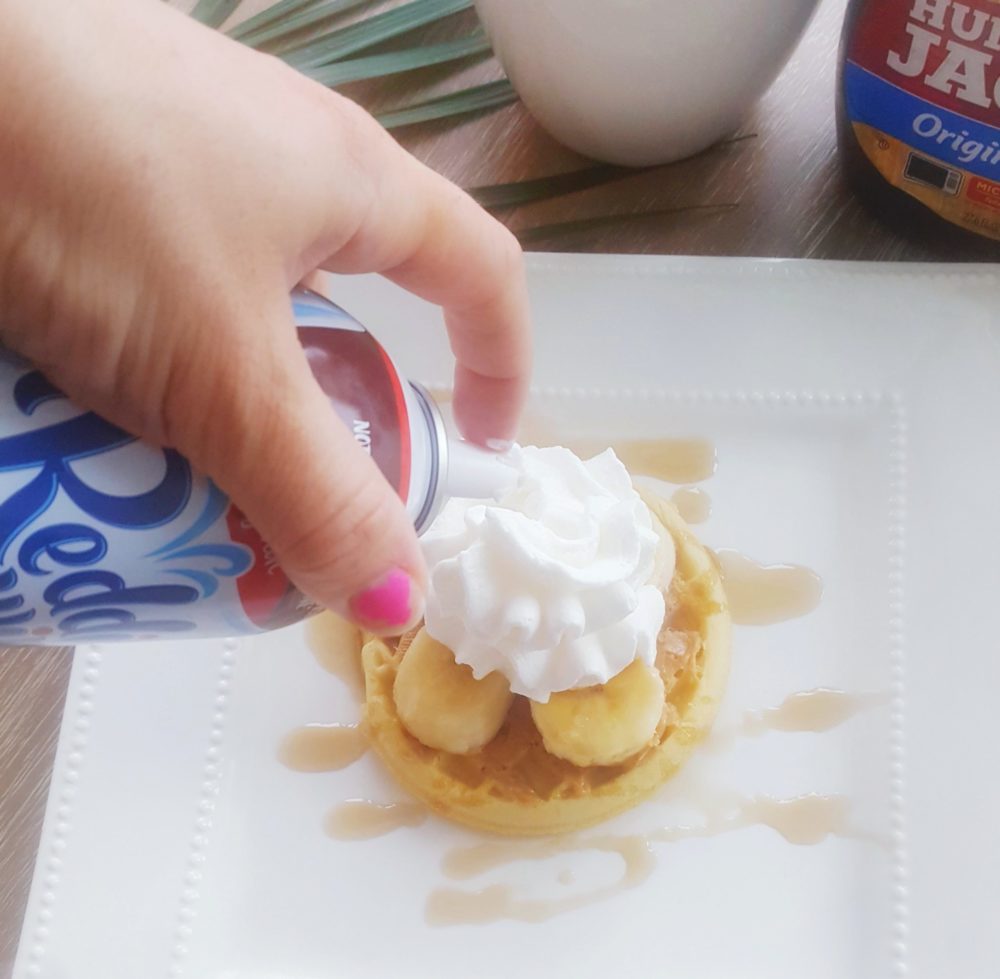 Eggo Waffle with peanut butter banana and whip cream toppings for a fun waffle bar