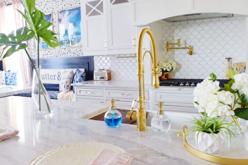 Modern Coastal Glam Kitchen Makeover Coastal Kitchen Design Ideas white farmhouse sink marble countertops marble kitchen island brass faucet brass pot filler coastal backsplash white backsplash