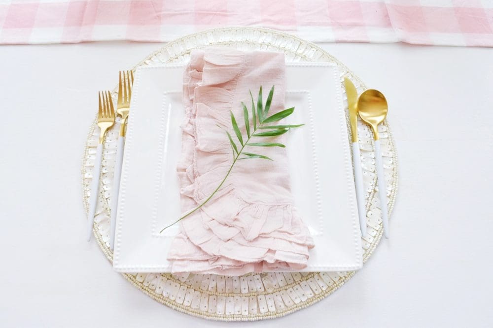 gorgeous spring table setting ideas using tropical palm leaves, ruffled table napkins, pink gingham tablecloth