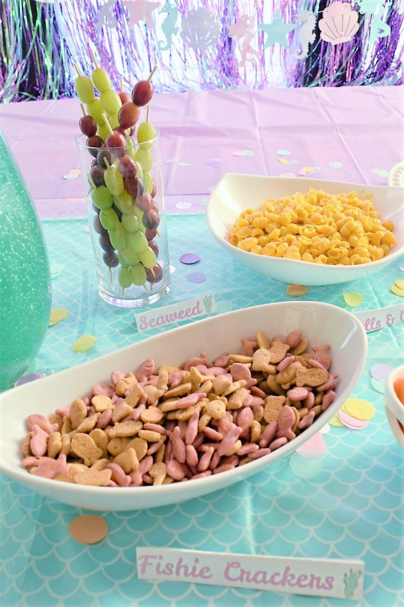 Mermaid Themed Birthday Party food ideas and party supplies food table including fishie crackers, seaweed, and shells and cheese 