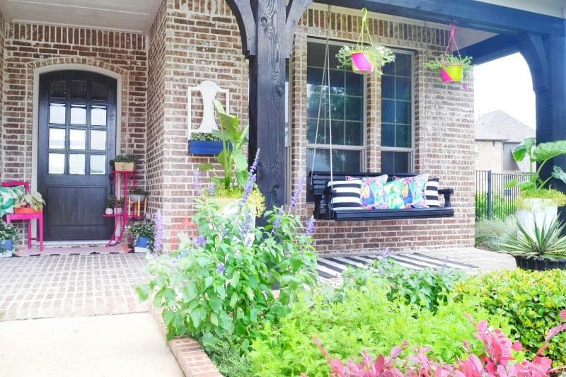 front porch with swing and colorful plants and decor