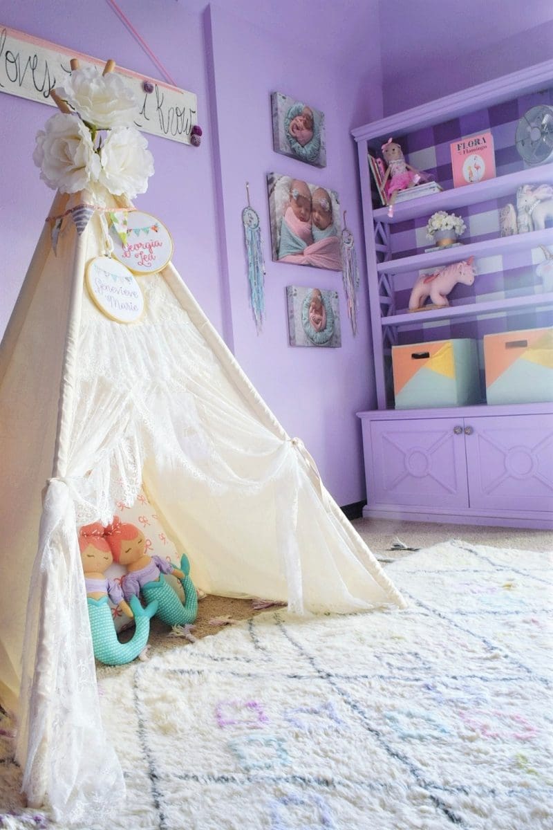 little girls bedroom with teepee with light purple bookcase and buffalo check print