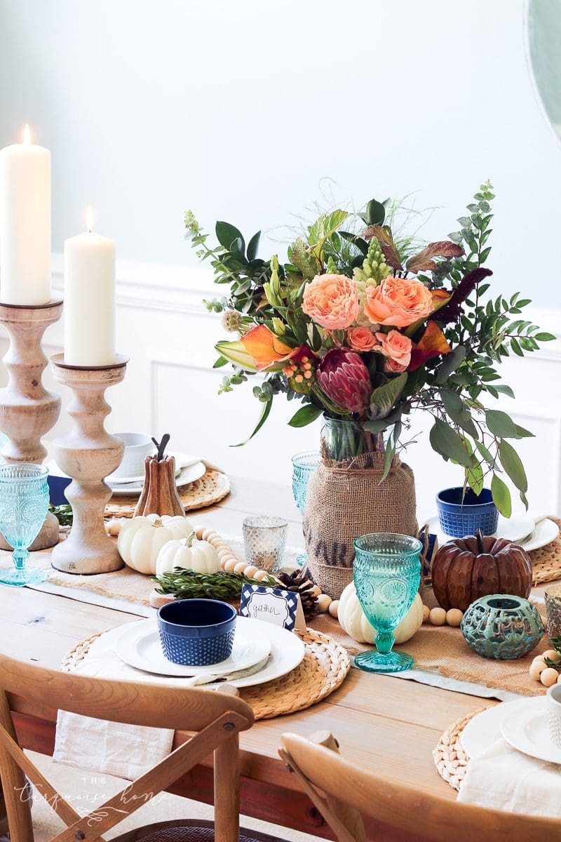 farmgirl flowers fall centerpiece with pillar candles and turquoise blue drinking glasses