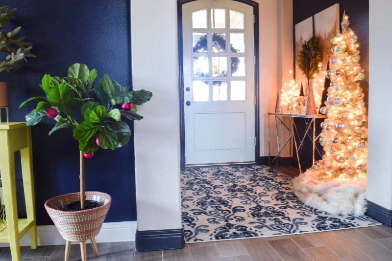 front door entryway with blue and white rug and dark painted accent walls