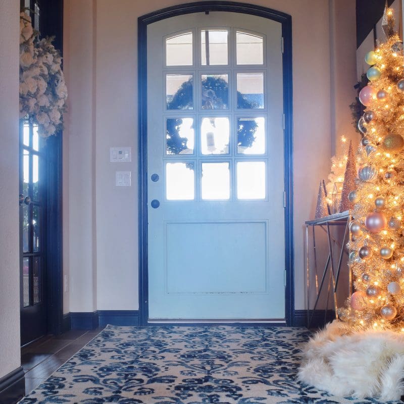 front door entryway Christmas decor with Christas tree and rug