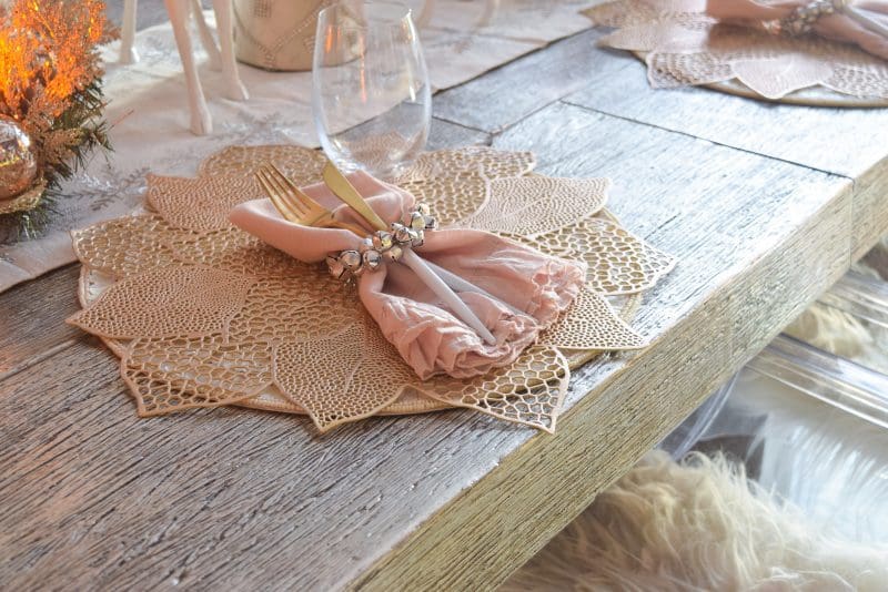 silver dining table with gold poinsettia placemat and jingle bell napkin ring