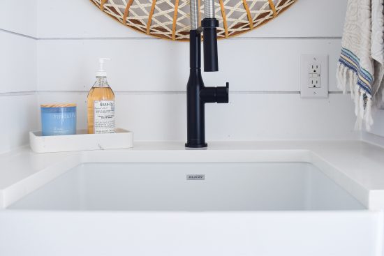 matte black faucet with shiplap walls and farmhouse sink